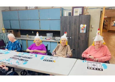 Four female residents playing bingo while wearing chicken hats